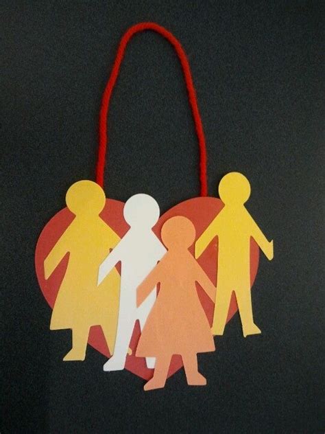 an ornament with paper cutouts of people holding hands and heart on ...