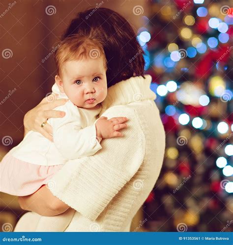 Mother Brunette Embraces Little Cute Chubby Baby Girl in a White Stock