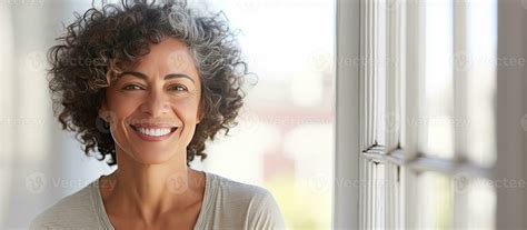 Happy older Hispanic woman enjoying retirement standing by window and