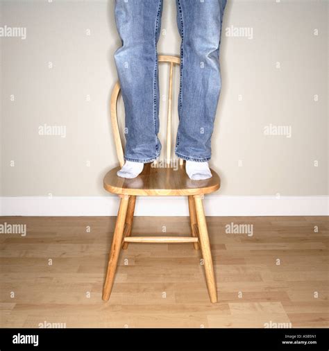 man standing  chair  reach  high stock photo alamy