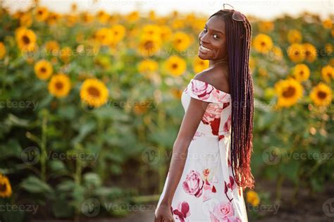 Pretty young black woman wear summer dress pose in a sunflower field