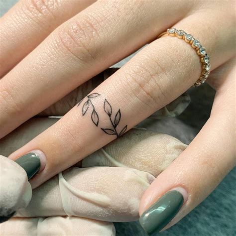 Minimalistic leaves ring tattoo located on the finger.