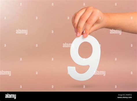 Number nine in hand. A hand holds a white number 9 on a red background ...