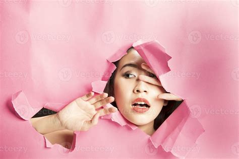 Young beautiful Asian woman expression through torn paper hole 24546385