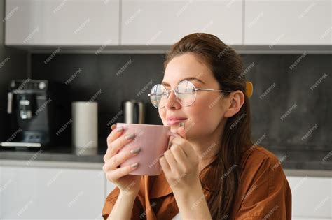Портрет молодой женщины, отдыхающей с чашечкой чая, пьет чай на кухне ...