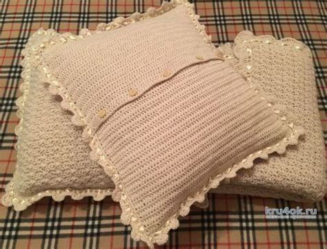 two knitted pillows sitting on top of a plaid blanket