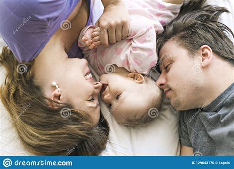 Portrait of Beautiful Young Parents and Cute Baby on Bed Stock Photo ...