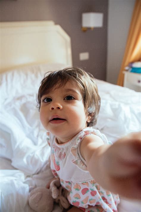 "Funny Baby Girl Grabbing Camera On A Bed" by Stocksy Contributor "Inuk