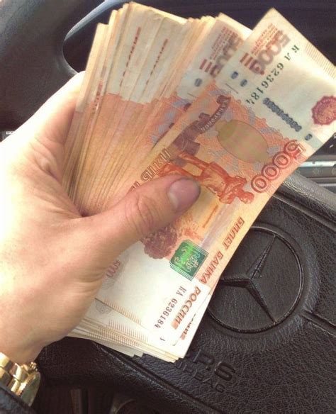 a person is holding out their money in the back seat of a car or truck