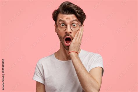 Surprised young European male expresses great confusion, keeps hand on ...