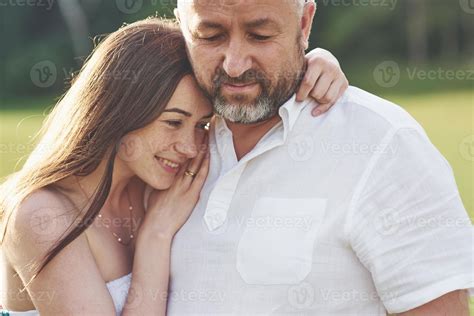 Handsome old man and beautiful young girl are hugging, daughter and her