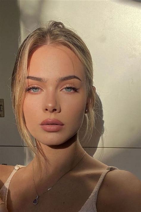 a woman with blue eyes and blonde hair is posing for a photo in front