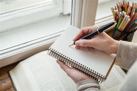 Mujer joven escribiendo memos frente a una ventana grande | Foto Premium