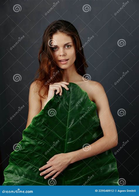 Pretty Woman with Naked Body Hiding Behind Palm Leaf Stock Photo