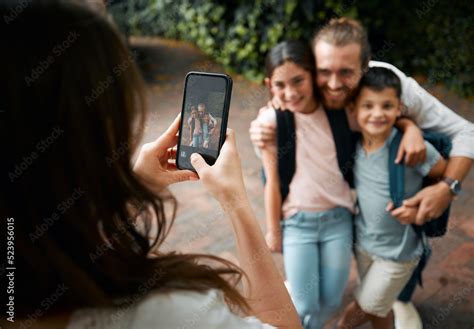Mother taking a family photo on her phone of her happy little children ...