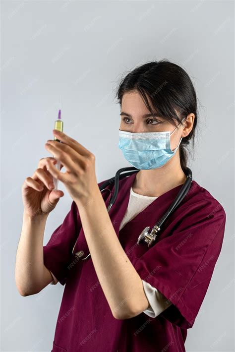Premium Photo | Young female nurse holds a syringe with a needle in her