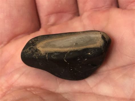 Smooth shiny black rock with tan/grey interior. Int can be scratched ...