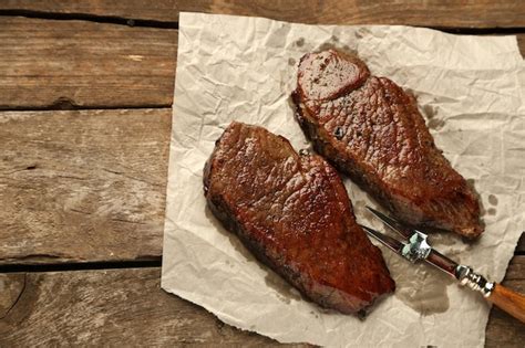 Composición con sabrosa carne asada en hojas de papel tomates y ramitas ...