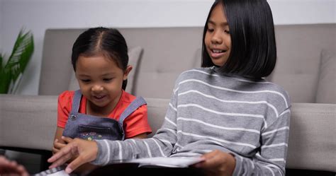 Handheld shot of Asian older sister teach younger sister to read book