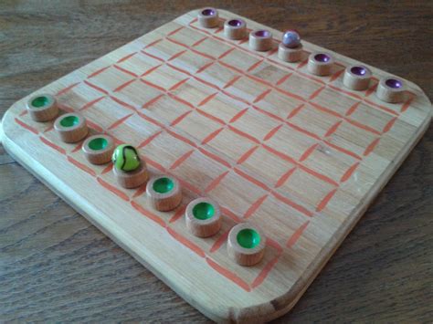 a close up of a wooden board game on a table with green and purple beads