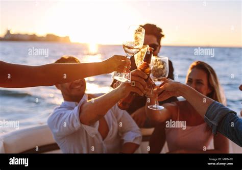 Sunset boat party with young people toasting drinks. Group of men and ...