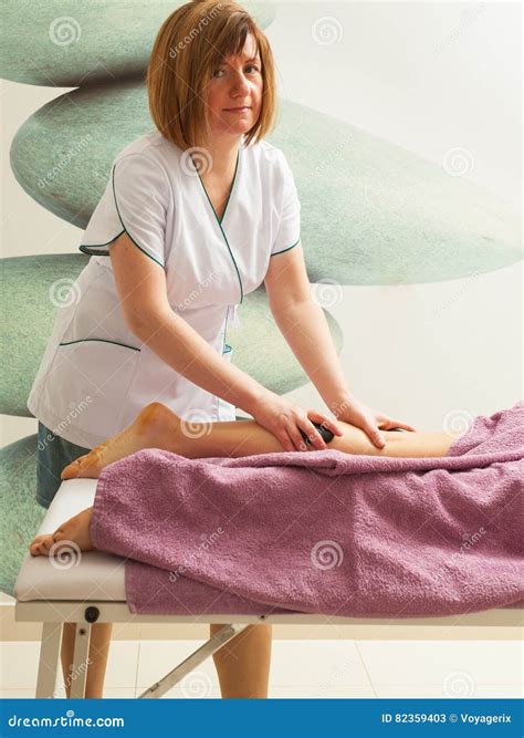 Masseuse Doing Legs Massage with Hot Stones Stock Image - Image of