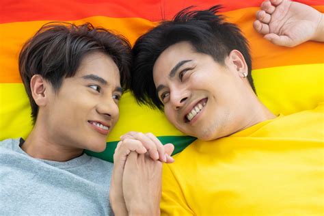 Portrait of young gay homosexual couple lying down together on the bed ...