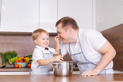 Dad and son cooking together in the kitchen preparing food, having fun