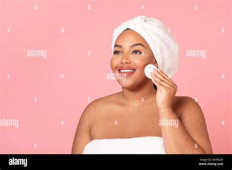 Skincare routine. Happy black chubby woman cleansing skin with cotton ...