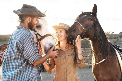 contento Pareja teniendo divertido con caballos dentro estable - joven