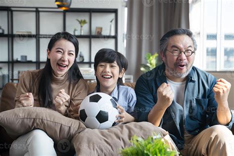 familia asiática viendo partidos de fútbol en la televisión y