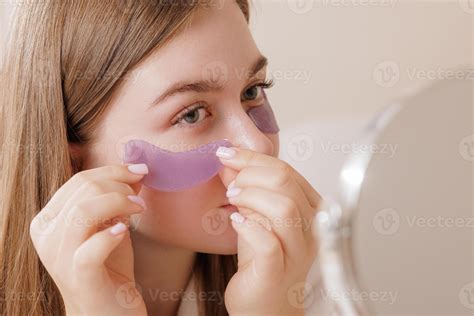 Woman uses purple under-eye patches for hydration, de-puffing, and skin