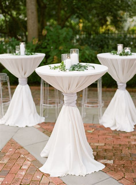 white pillar candles  greenery atop cocktail tables cocktail hour