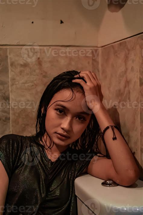 Hot and wet Asian girl poses with sensual style while wearing black wet