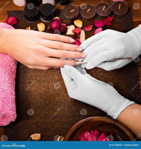 Closeup Finger Nail Care by Manicure Specialist in Beauty Salon. Stock