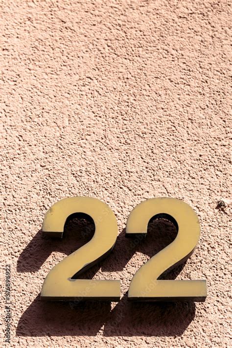 Number 22 twenty-two golden metal address sign fixed onto textured ...