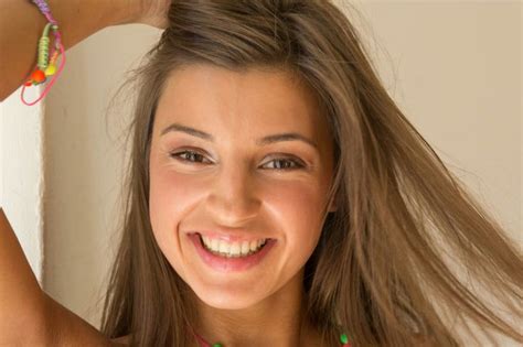 a woman with long hair smiling and holding her hand up to her head ...