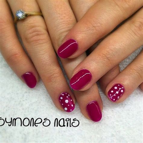 Raspberry gel nails with spotty nail art.