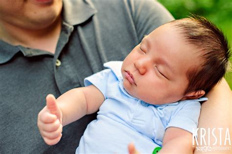 newborn baby boy giving thumbs up while sleeping during outdoor ...