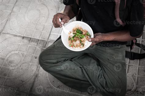 poor man homeless with dirty hands eating eating food at street road