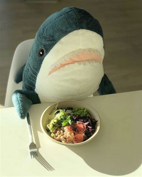 a stuffed shark sitting at a table with a bowl of food