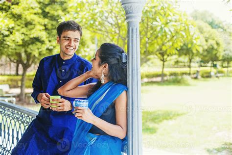 Beautiful Indian couple wearing traditional clothes drinking coffee or