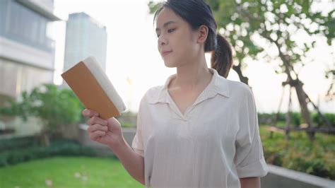 Pretty asian woman reading stories poetry from small book in the