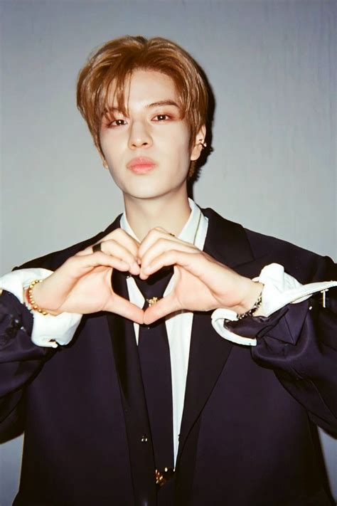 a man in a suit making a heart with his hands