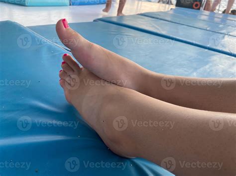 Woman is standing barefoot on floor in front of gymnastic mat and