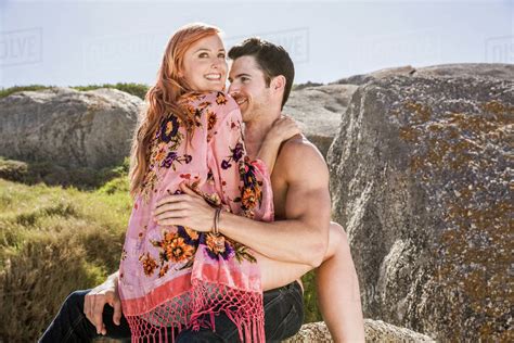 Couple outdoors, woman sitting on man's lap, face to face - Stock Photo - Dissolve