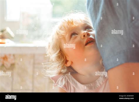 the child hides behind his mother, holding on to her skirt Stock Photo ...