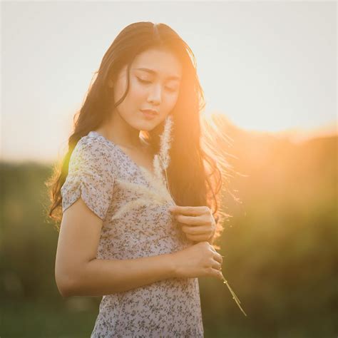 Dreamy Asian lady with dry plant in countryside · Free Stock Photo
