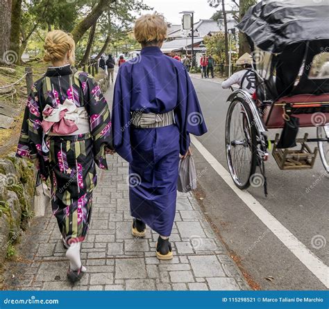 Japanese Couple in Traditional Clothes Walking Down the Street Near a