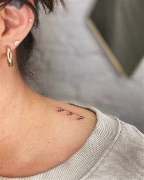 Lettering tattoo "ggg" located on the top of shoulder.